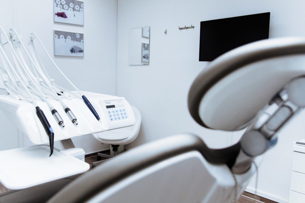 A dentist's chair with some tools behind it.