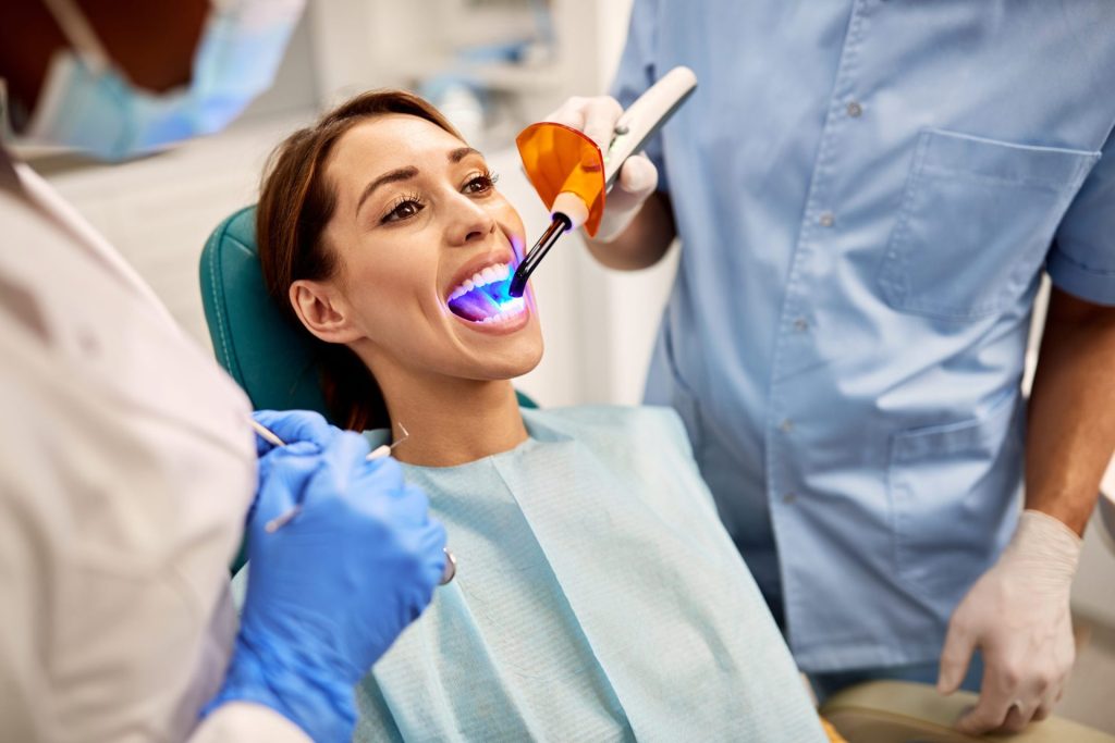 Dentist using a curing light on a patient's teeth