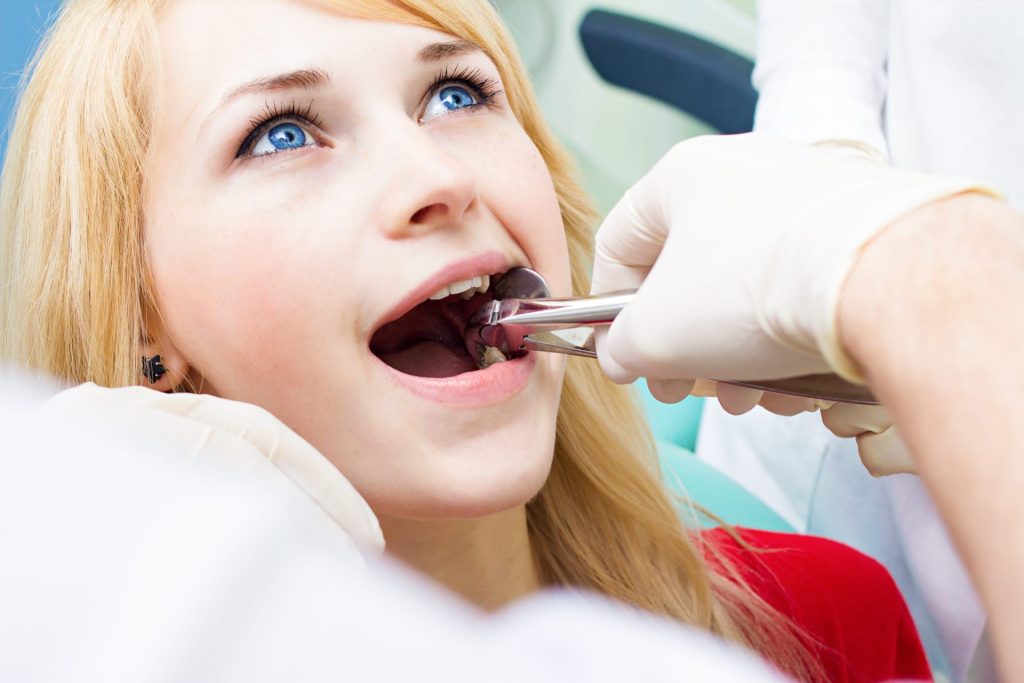 Patient having a tooth removed with dental forceps