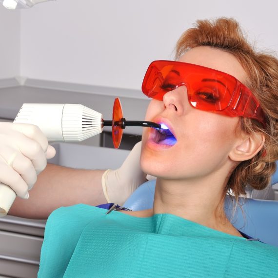 Woman in protective glasses having a filling set with a curing light